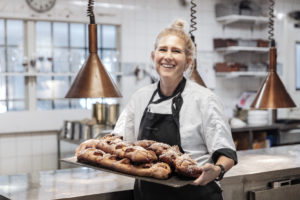 Glas bagerska håller i plåt med nygräddade kanellängder i köket på Friibergh.
